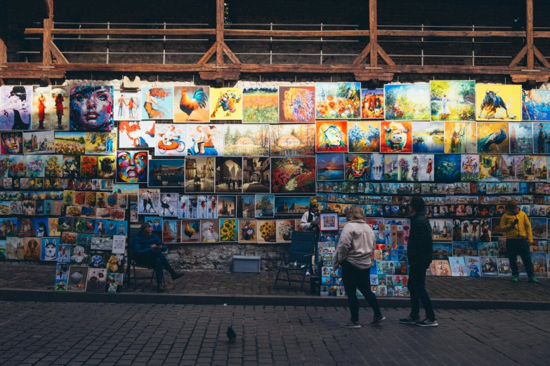 a wall filled with paintings and people next to each other