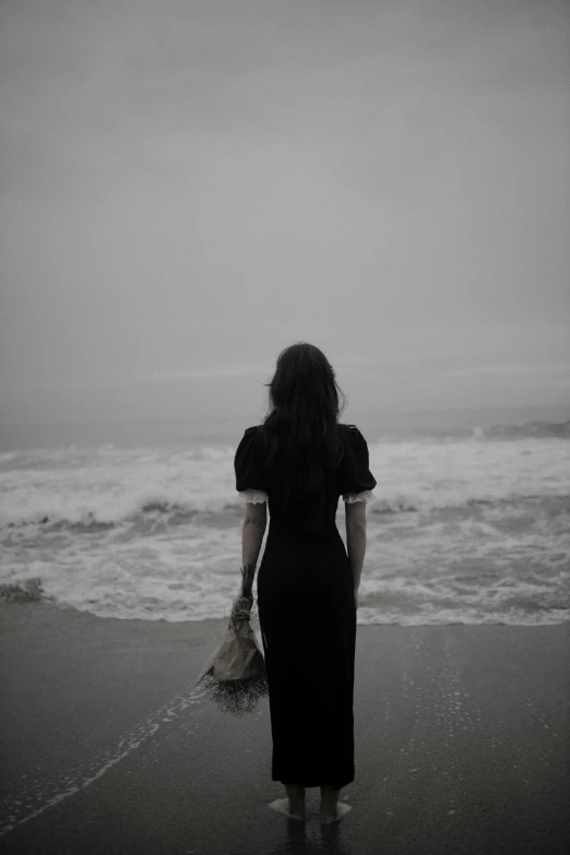 a woman is standing on the shore near the water