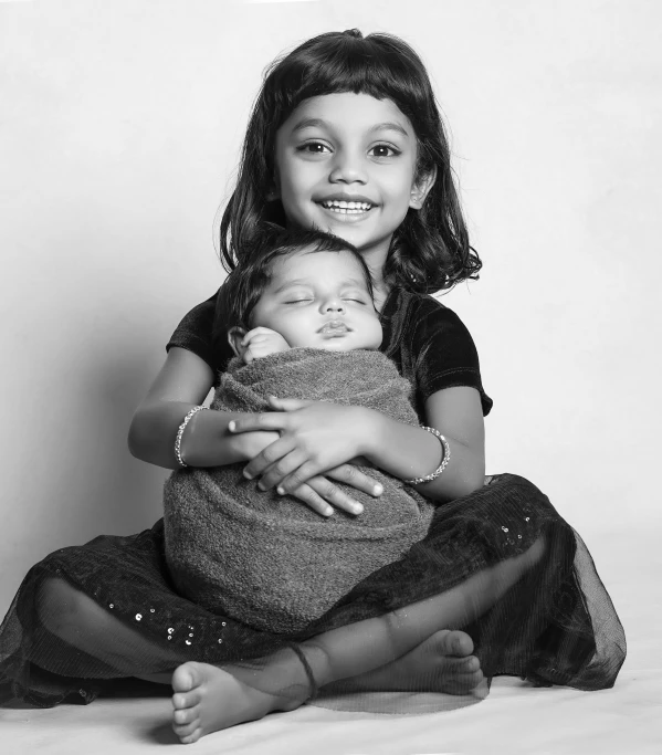 an adorable little girl hugging her infant in her arms