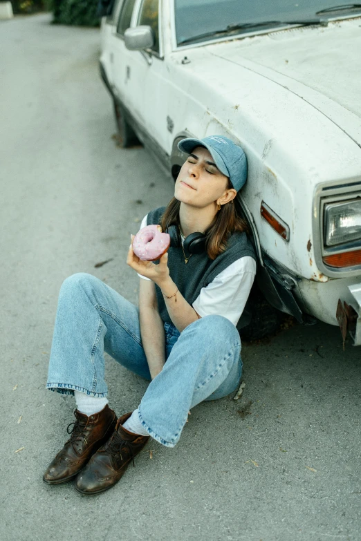 a woman is sitting under a parked white car