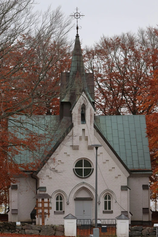 a church sitting in the middle of a park with autumn trees