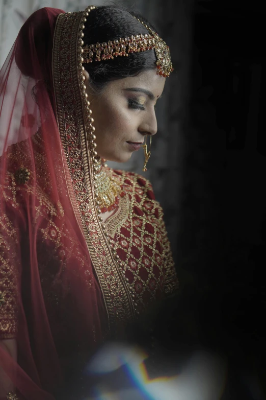 a woman in a red indian outfit with gold jewellery and pearls