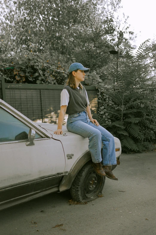 a person that is sitting on the hood of a car