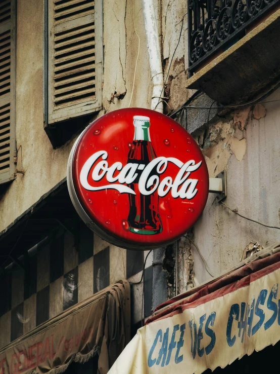 a neon coca - cola sign on a building along the street