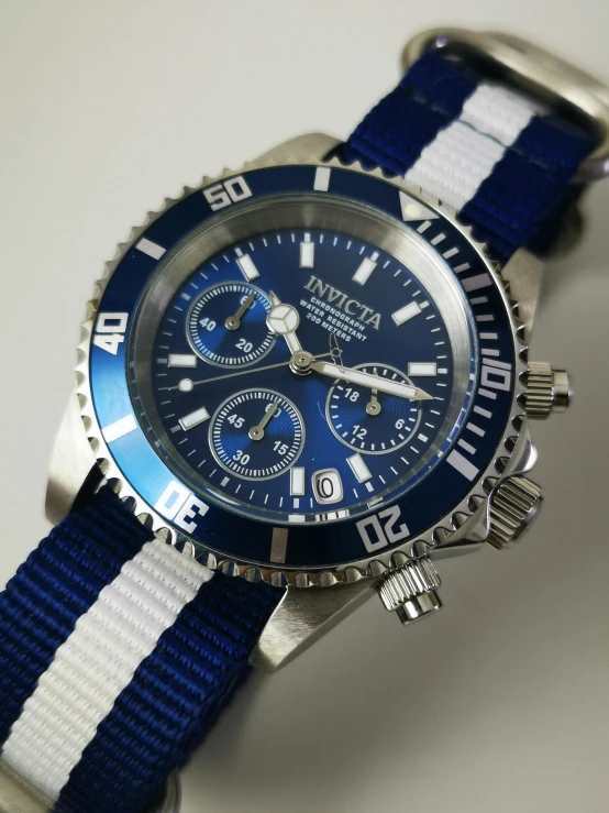 a wrist watch with a striped band and a blue face