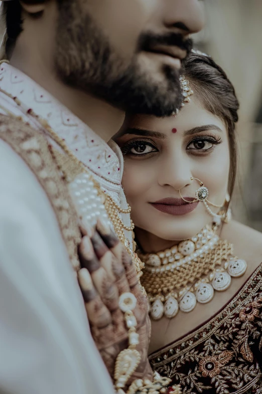 two women are wearing veils, a white and gold outfit and necklaces