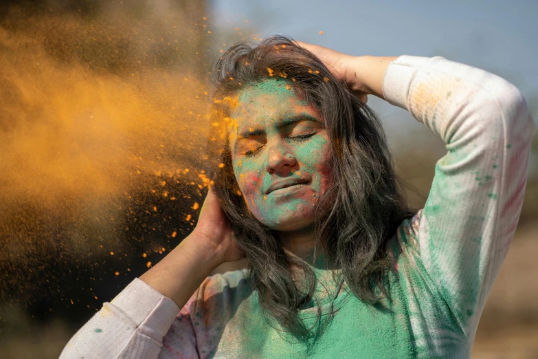 a woman with her hair in the wind and colored dust