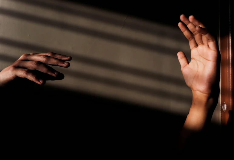 a close up of two hands reaching out of the sun