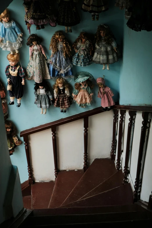 doll figurines are lined up against the wall of the stairs