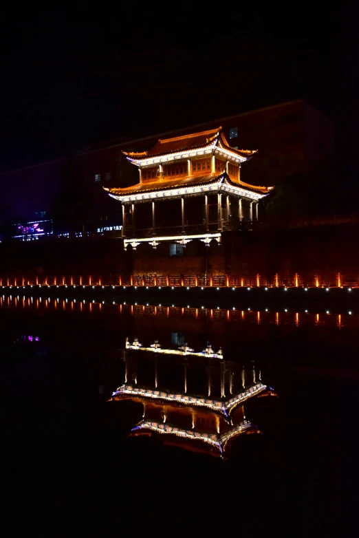 an illuminated building and it's reflection in the water