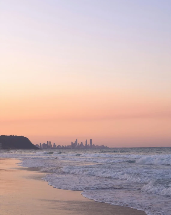 a couple walking along the beach in front of the city