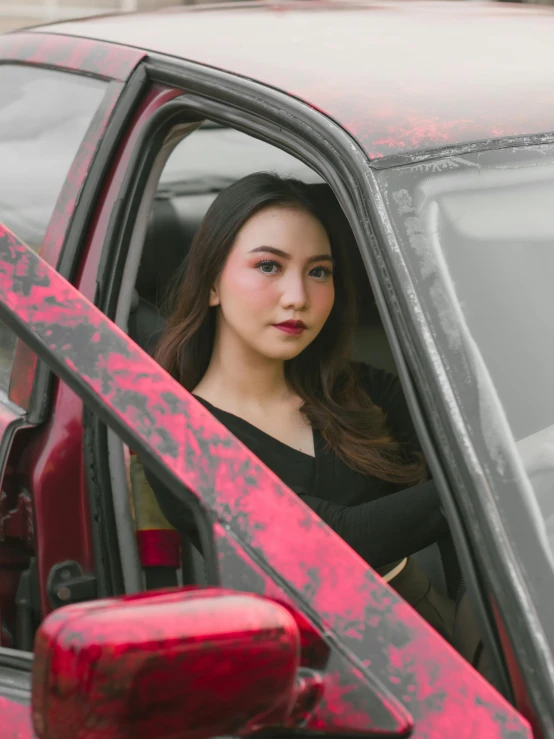 a young woman is sitting in a red car
