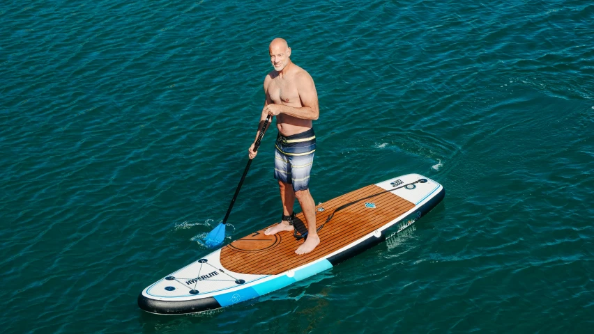 an aerial view of a man in the water on his paddle board