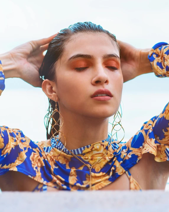 a woman with large ear rings and an open shirt on standing