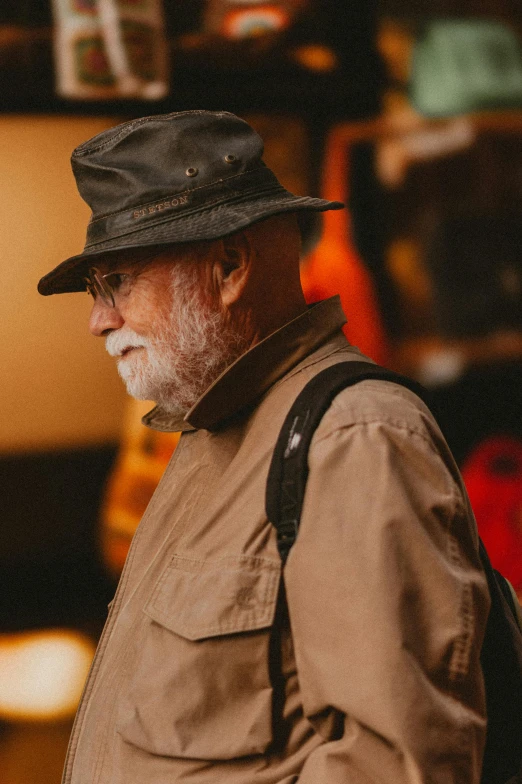 an older man with a beard, wearing a brown hat and tan jacket