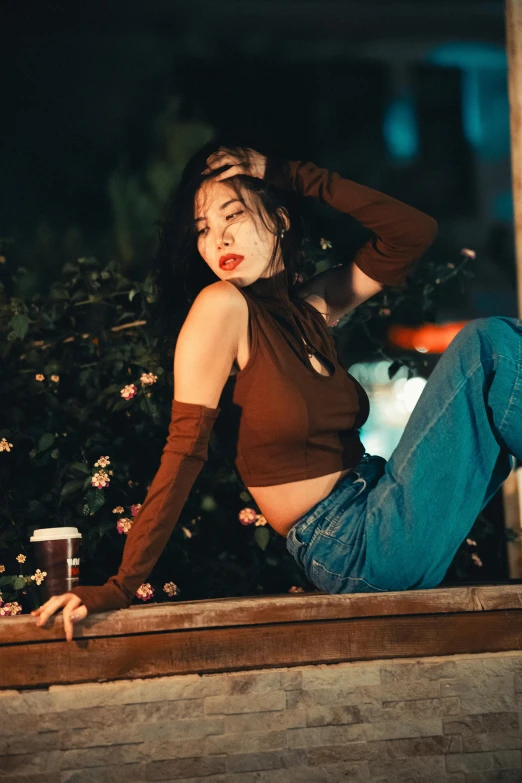 a woman sitting on the curb in jeans and brown shirt