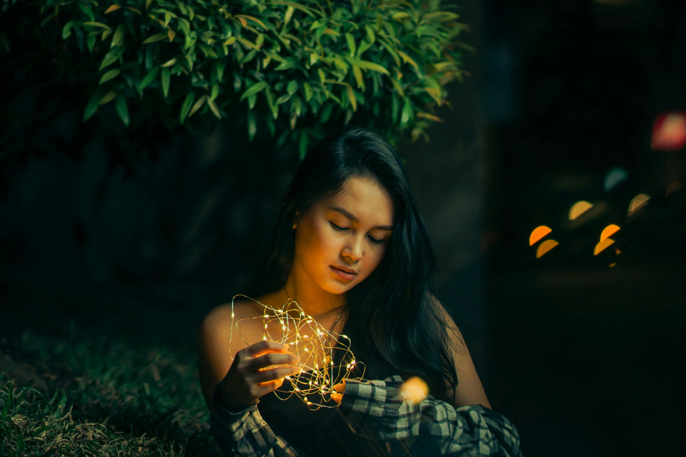 a woman is sitting in the grass holding flowers