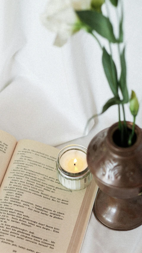 open book with candle in the middle on table