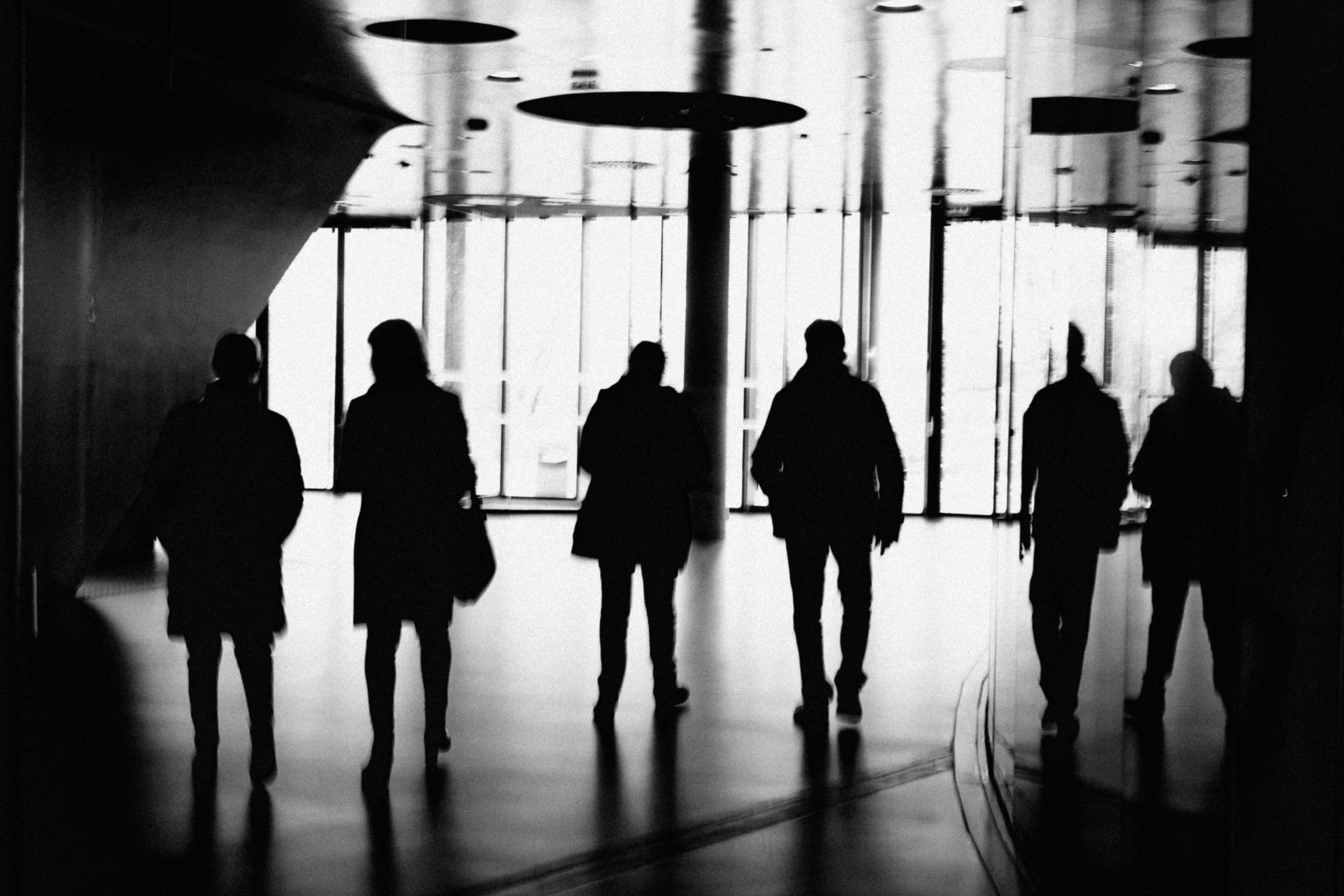 black and white pograph of people walking in front of building