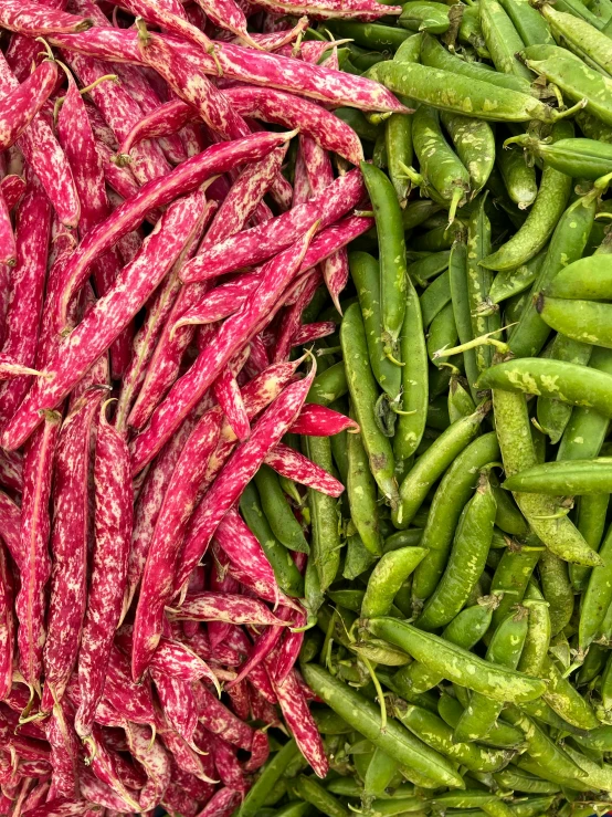 a bunch of purple peas sitting next to green beans