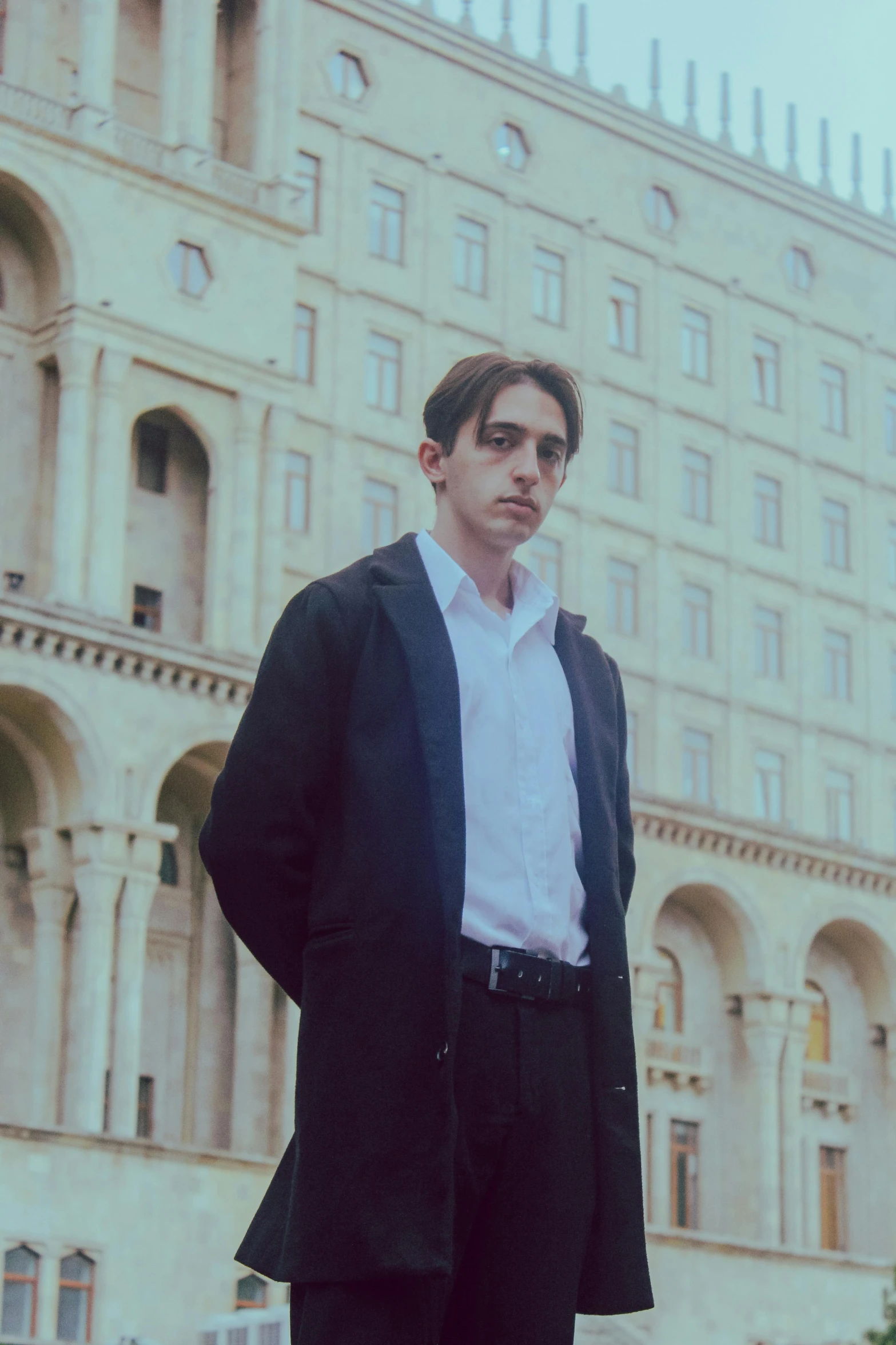 the man is standing outside in front of a large building