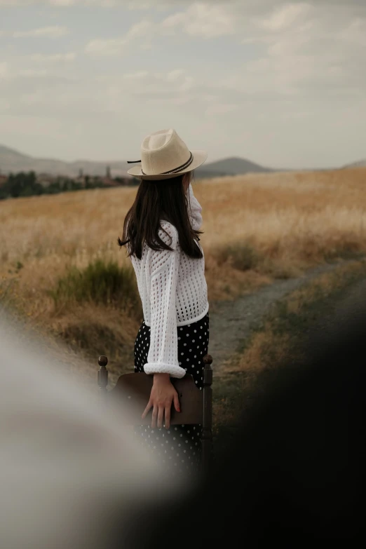 a person with a hat sitting on the back of a suitcase