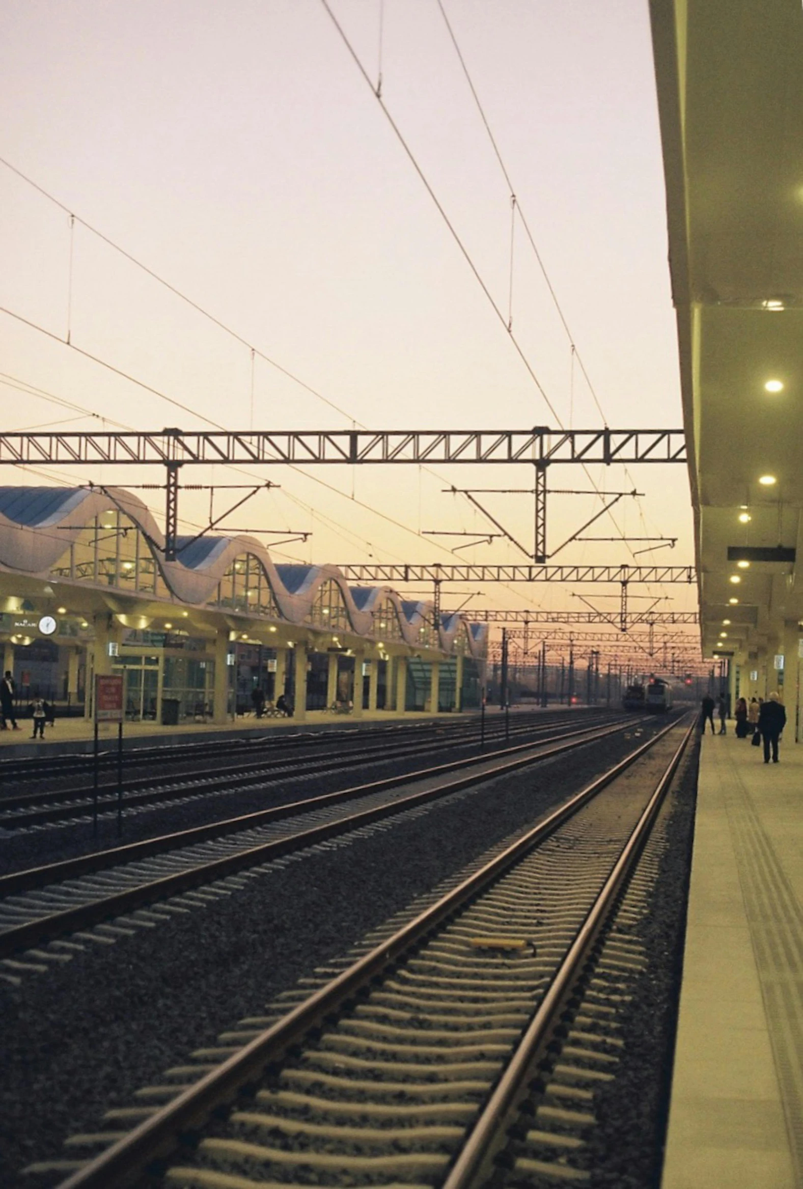 people are walking on the railroad tracks near a train station