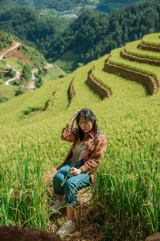 a woman sitting on a green rice field