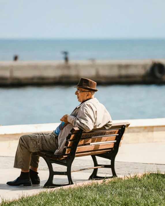 an old man sitting on a bench near the ocean