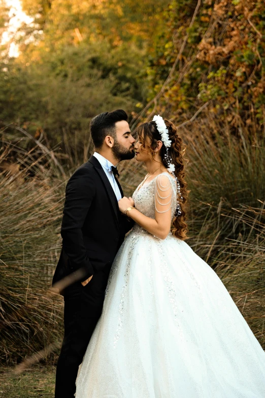 two people in wedding dresses kissing near bushes