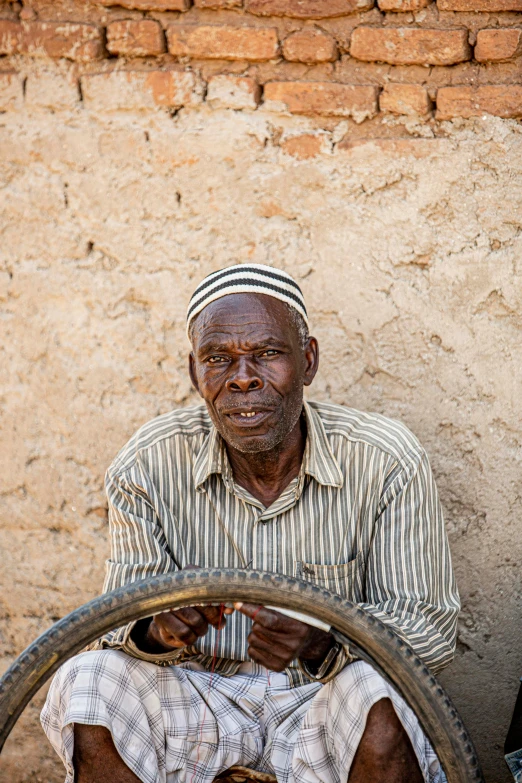 a man wearing a hat is holding a bicycle wheel