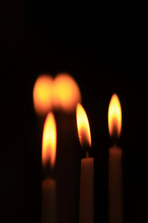 three lit candles in the dark with bright light