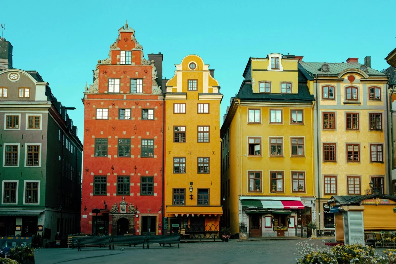 multiple colorful buildings with benches and people in front