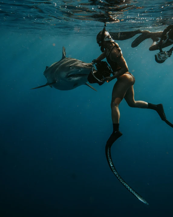 a person in a diving mask and boots underwater near a big shark