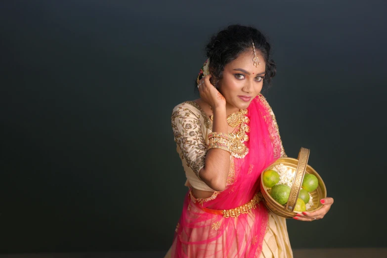 an indian woman is holding a basket with apples