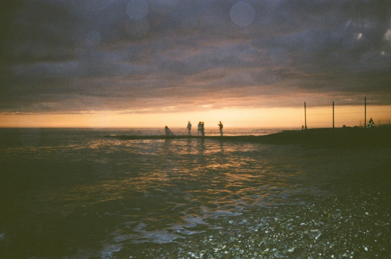 people are standing on small poles in the water at sunset