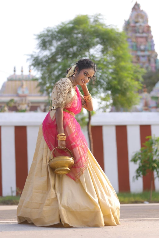 a lady in a pink and yellow dress with a gold purse on her shoulder