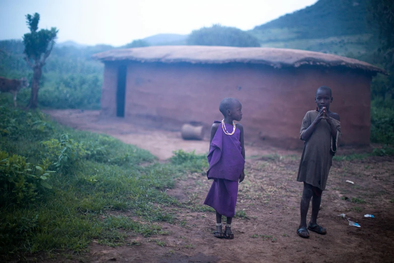 two children outside a village in the rain