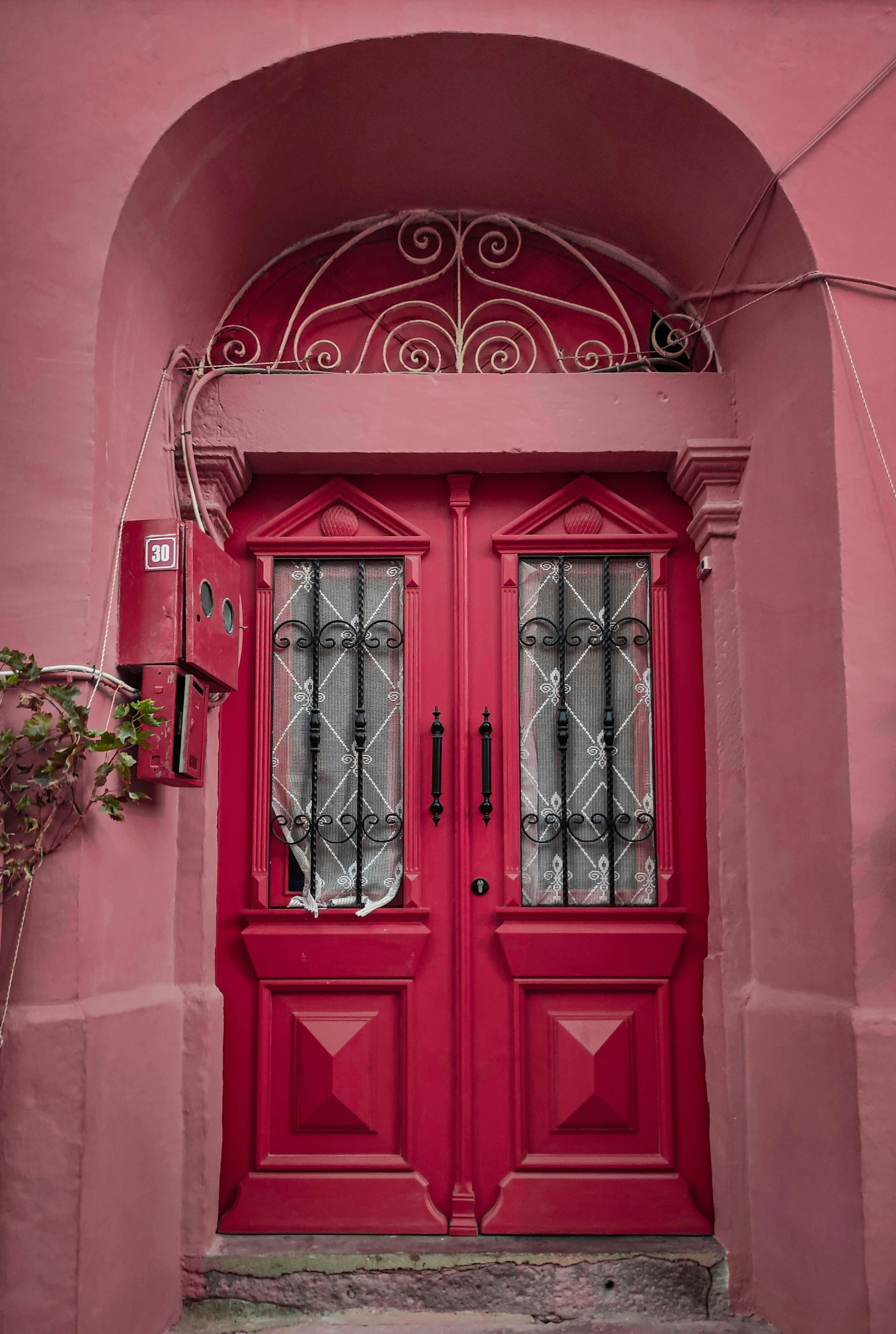 a red door is open in front of a pink building