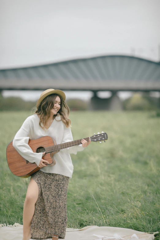 a woman in a hat and dress is playing the guitar