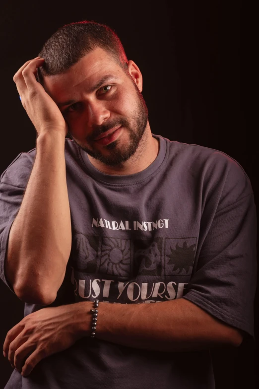 a man in grey shirt with his hands folded over his head