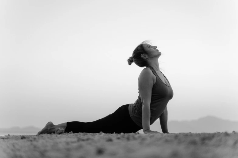 a pregnant woman practices yoga in a field