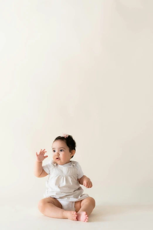 a baby sits on a white surface