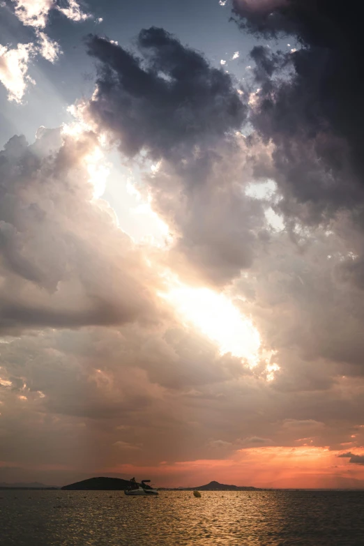 the sun shining through the clouds over water