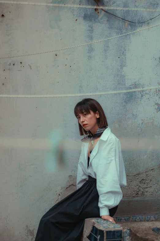 a young woman sitting on top of an old brick wall