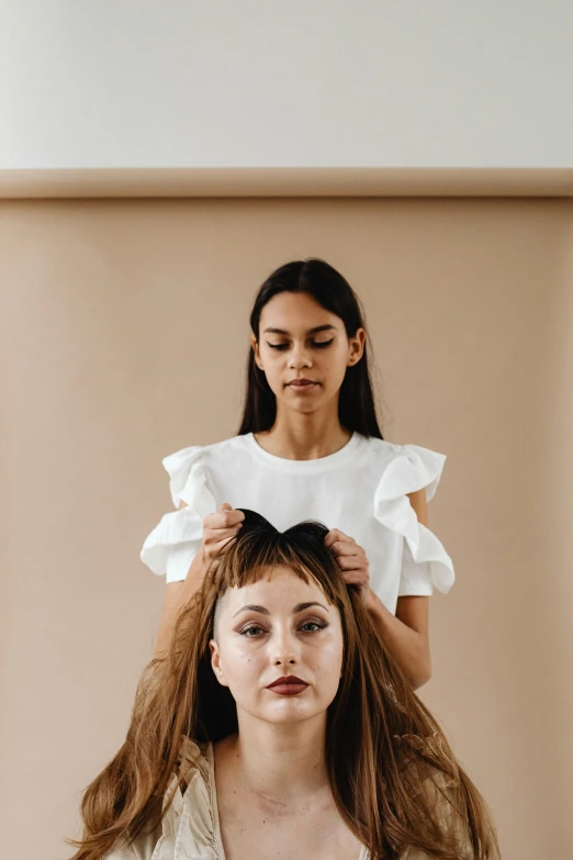 two women are looking over the top of a brown chair