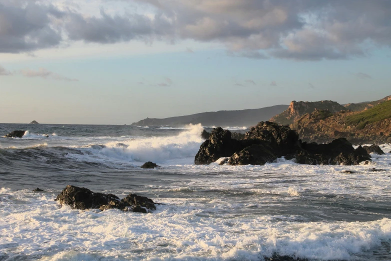 rough waters with crashing waves and some hills