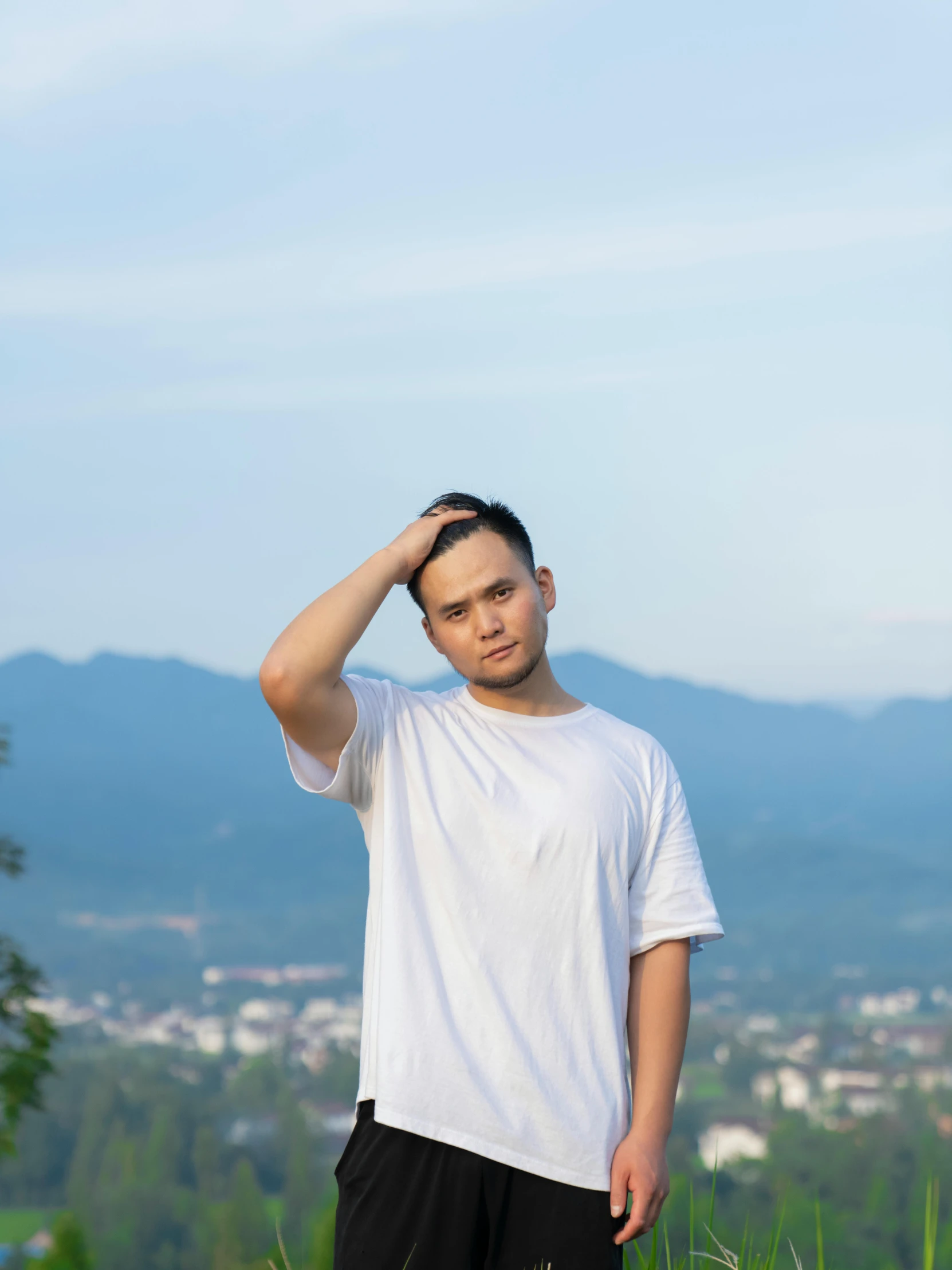 a young man stands on top of a hill near grass and flowers