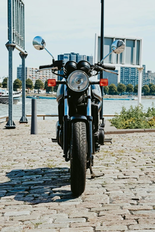 a motorcycle parked on a cobblestone path next to a river