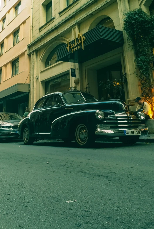 an old car sitting next to a car parked on the street